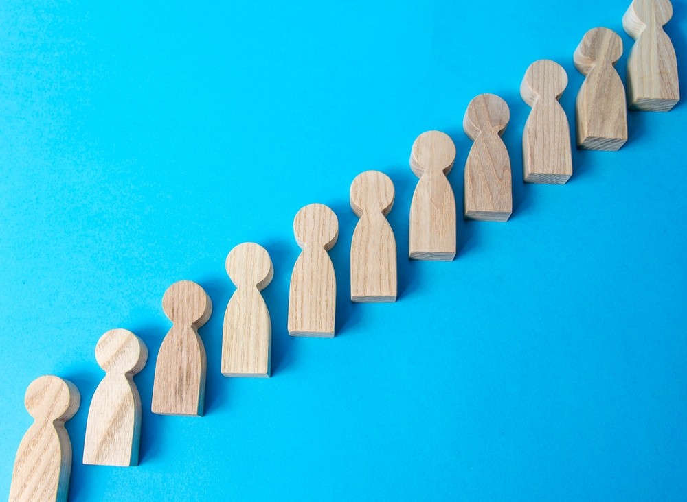 Wooden figures of people in ascending row to represent an escalation process