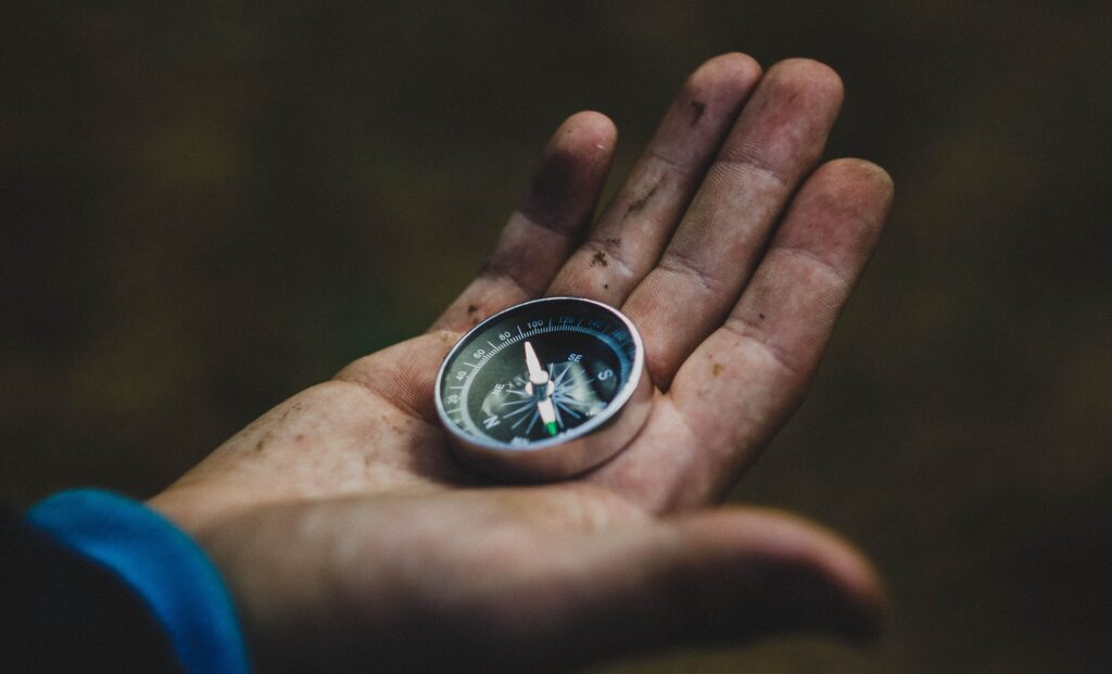 A man's hand holding a compass. Indicative of process mapping as a guide.